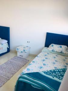 1 Schlafzimmer mit einem Bett mit blauem Kopfteil und 2 Teppichen in der Unterkunft Shipa's nubian house in Assuan