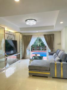 een grote woonkamer met een bank en een televisie bij Pattaya Pool Villa39A 300 mater to beach gate exit in Pattaya South