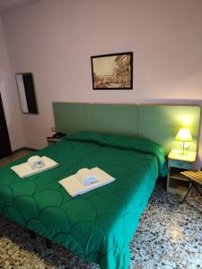 un letto verde in una stanza con due tavoli sopra di Hotel Etrusco a Sesto Fiorentino