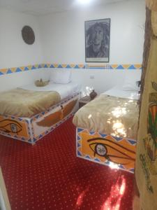 peace garden hostel & camp في الأقصر: سريرين في غرفة مع سجادة حمراء