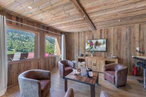 un soggiorno con pareti in legno, tavolo e sedie di Chalet Kashmir 5MIN des pistes en voiture parking privé, spa, sauna a Les Allues