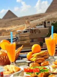 einen Tisch mit Teller mit Speisen und Orangensaft in der Unterkunft Golden Pyramids View Inn in Kairo