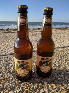 dos botellas de cerveza sentadas en la playa en Les Volets Bleus-Charmante maison entièrement équipée face à la mer pour 2 à 6 personnes, en Bernières-sur-Mer