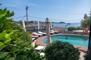 a swimming pool with umbrellas and chairs next to a building at Villa Nina Adult only in Skiathos