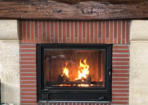 a brick fireplace with a fire in it at Les Volets Bleus-Charmante maison entièrement équipée face à la mer pour 2 à 6 personnes in Bernières-sur-Mer