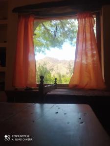 una ventana con una cortina naranja en una habitación en Cabaña El Paraíso en Tinogasta