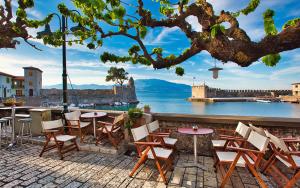 a patio with tables and chairs and a view of the water at my own way in Nafpaktos