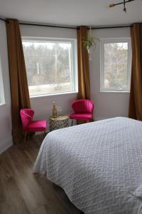 a bedroom with a bed and two pink chairs at 4 Guest Suite with Waterfront Views at Fancie's PEC in Belleville