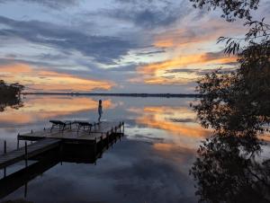 a person standing on a dock on a lake at sunset at 4 Guest Suite with Waterfront Views at Fancie's PEC in Belleville