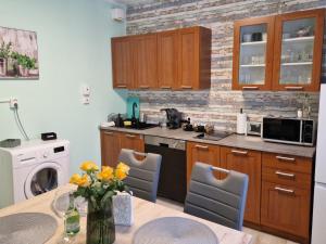 a kitchen with wooden cabinets and a table with yellow flowers at Veludo Apartments Centrum free parking in Banská Bystrica