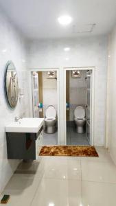 a bathroom with two toilets and a sink and a mirror at 106 MAIN STREET by ZamanJa Betong in Betong