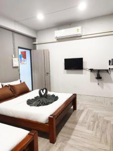 a bedroom with two beds and a tv on the wall at 106 MAIN STREET by ZamanJa Betong in Betong