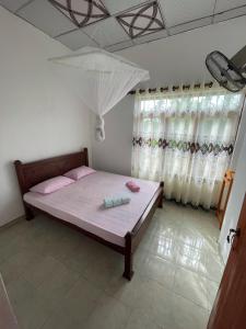 a bedroom with a bed with pink pillows and curtains at Janaka's House in Dickwella