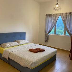 een slaapkamer met een bed met een blauw hoofdeinde en een raam bij Selesa Hillhomes Cosy House in Bentong