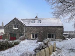 a brick house with snow on the ground at The Drumlins Cottage in Ulverston +18 photos