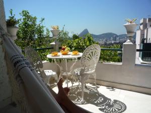 a person laying on a balcony with a table and chairs at Guesthouse Bianca in Rio de Janeiro