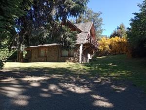 a stone house with a large yard in front at LA Nevadita, Chalet cabin located near the center- It includes suite room with double bed and another 2 bedrooms with two singles beds- Living room fireplace, Hot water, WI-FI in Villa La Angostura