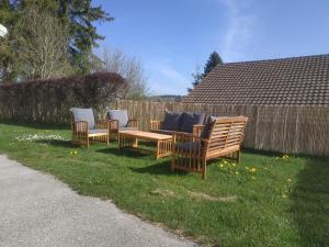 3 sillas de madera y una mesa en el césped en GRAND APPARTEMENT COSY DANS MAISON DE CAMPAGNE, en Saint-Pierre