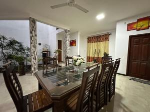 a dining room with a glass table and chairs at Naturus Villa Thalpitiya in Panadura