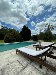 a pool with a bench and a table next to it at Quinta Siete Soles in Tandil