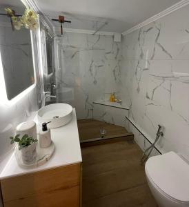 a white bathroom with a toilet and a sink at Avant-Garde Studio in Athens