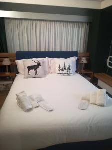 a bed with two towels and a deer and forest pillows at La Casa Shabby in Marilleva