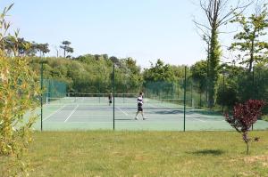 2 personnes jouant au tennis sur un court dans l'établissement Résidence Goélia Le Cordouan, à Soulac-sur-Mer