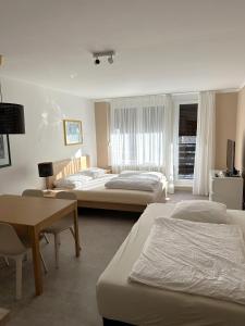 una camera d'albergo con tre letti, un tavolo e una scrivania di BovecEnter Apartments Kaninska vas a Bovec