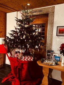 uma árvore de Natal com presentes debaixo dela numa sala em Maloja Kulm Hotel em Maloja