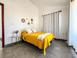 een slaapkamer met een bed met een gele deken bij Casa Violetas in Oaxaca City