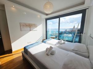 two beds in a room with a large window at Dios Ponte Finikoudes Beachfront Duplex Penthouse in Larnaka