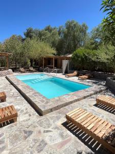 a swimming pool in a yard with benches around it at Hotel Corvatsch in San Pedro de Atacama