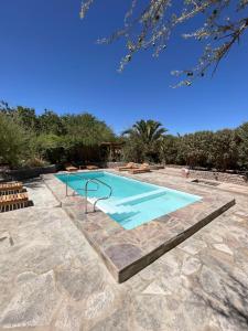 a swimming pool with a stone walkway around it at Hotel Corvatsch Chile in San Pedro de Atacama