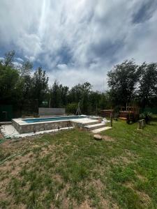 a swimming pool in a yard under a cloudy sky at Complejo La Rosa Molinari Cosquin in Córdoba