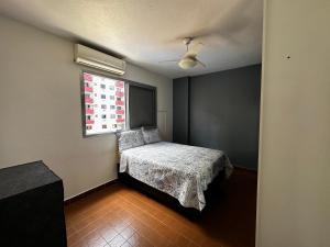 a bedroom with a bed and a window at Apartamento Boqueirao in Praia Grande