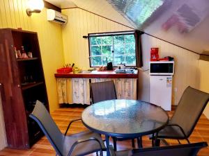 a kitchen with a table and chairs and a kitchen with a refrigerator at Studio Rava 1 Room Fare Tepua Lodge in Uturoa
