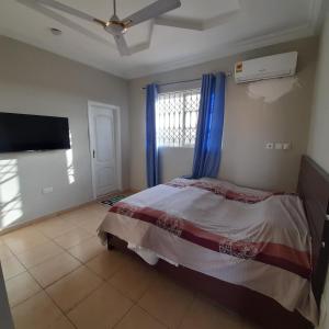 a bedroom with a bed and a flat screen tv at Atom Height Apartments in Tema