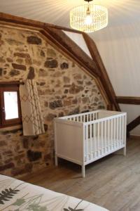 Cette chambre dispose d'un lit bébé et d'un mur en pierre. dans l'établissement La p'tite maison, à Orschwihr