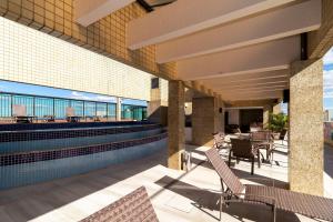 a patio with chairs and a swimming pool on a building at Apartamento em hotel 5 Estrelas Brasília - GMB0414 in Brasilia