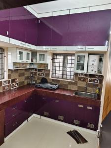 a large kitchen with purple cabinets and a sink at Alif serviced Apartment for Families and Executives in Tambaram