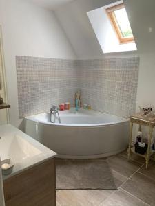 eine weiße Badewanne in einem Badezimmer mit Dachfenster in der Unterkunft Maison au cœur du Perche in Val-au-Perche