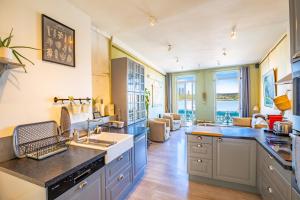 une cuisine avec des armoires bleues et un salon dans l'établissement Maison de ville en bord de Seine à La Bouille, à La Bouille