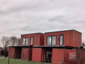 ein rotes Backsteingebäude mit Fenstern und einem Zaun in der Unterkunft Tiny House Betuwe in Tricht