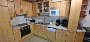 a kitchen with wooden cabinets and a sink and a microwave at Appartement Gletscher-Koje in Tux