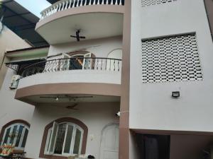 un homme assis sur le balcon d'une maison dans l'établissement Serene Homestay (Mini -For 2 to 3 Guest), à Panaji