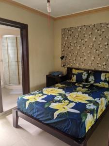 a bedroom with a bed with a blue comforter with yellow flowers at M & L Shared Apartment in Punta Cana