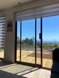 a room with sliding glass doors with a deck at Cabaña Viaducto Vista al Mar, Curanipe in Pelluhue