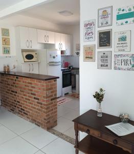 cocina con chimenea de ladrillo y electrodomésticos blancos en Buganville House Cabo Frio en Río de Janeiro