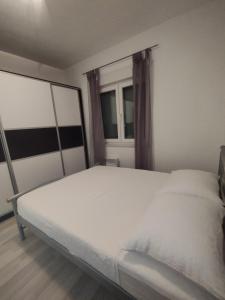 a white bed in a room with a window at Apartman Marija in Grude