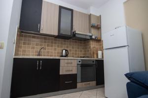 a kitchen with black cabinets and a white refrigerator at Odore di Mare con Jacuzzi in Durrës